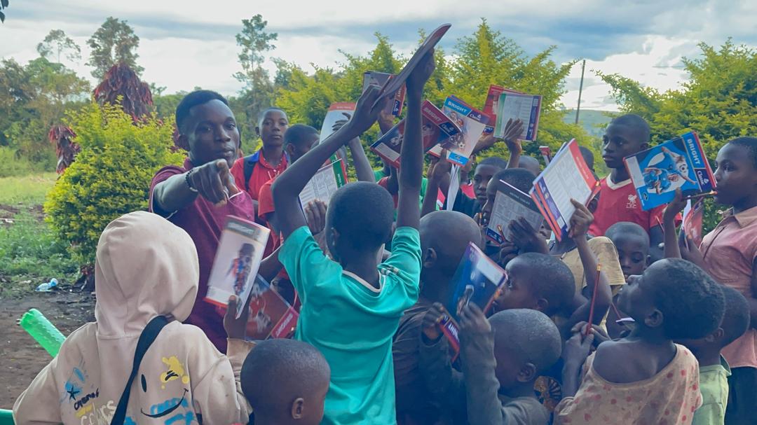 Children reaching up excitedly to receive new textbooks and pencils